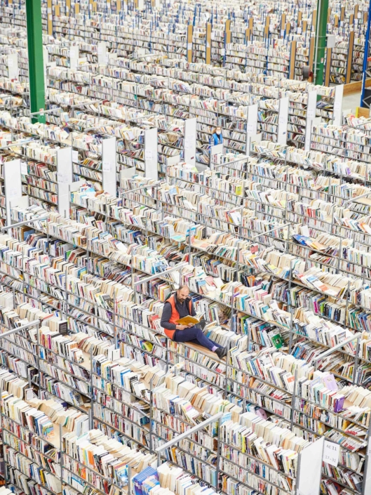 Homme lit un livre sur la bibliothèque d'un entrepôt contenant des millions de livres